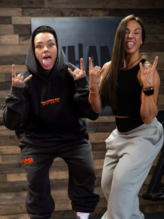 Founder Carly & Sponsored Athlete Fran celebrating together whilst wearing the faded black tracksuit and stone joggers 