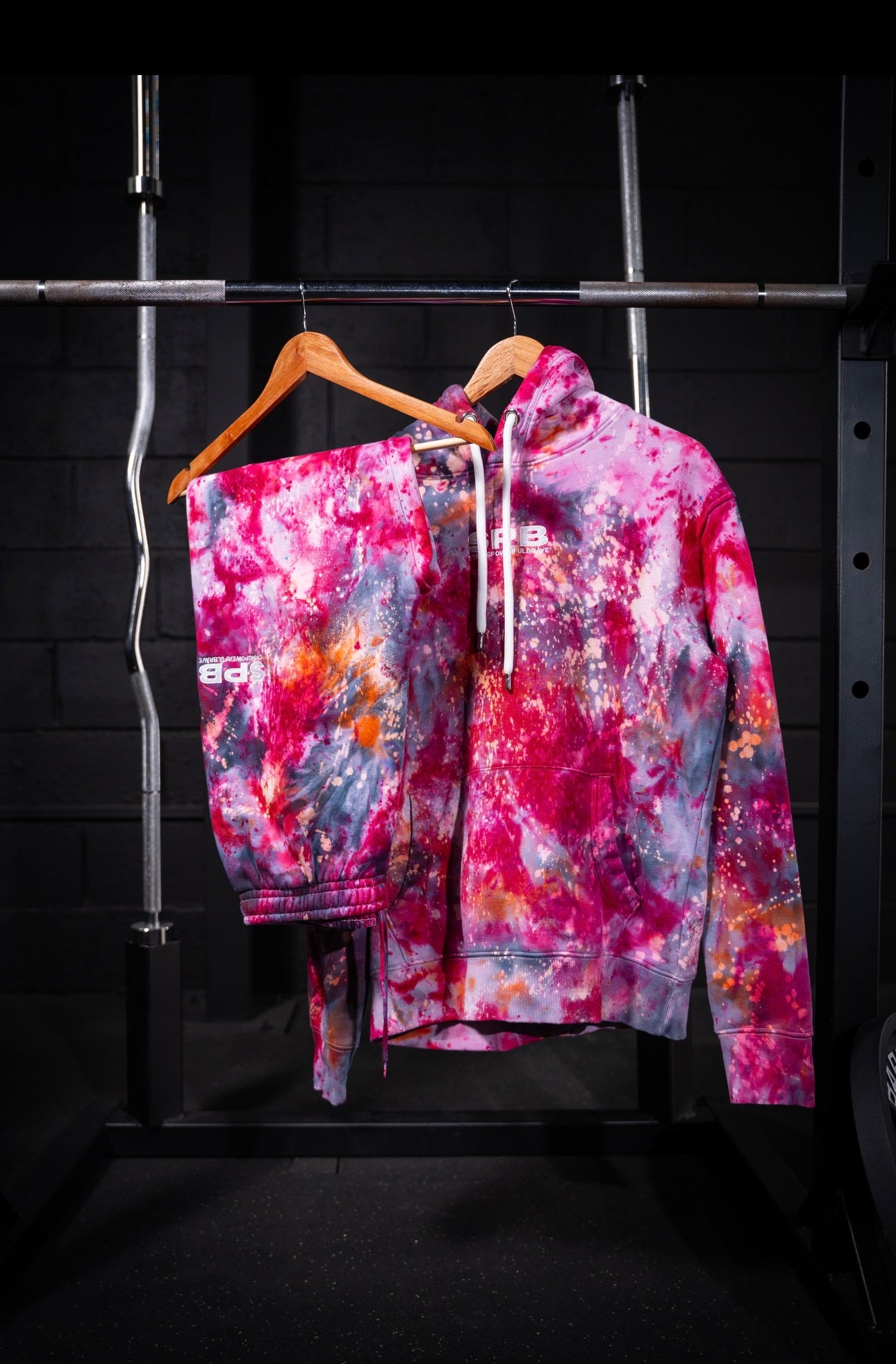 Pink rain tie-dye hoodie/set on a hanger against a dark background